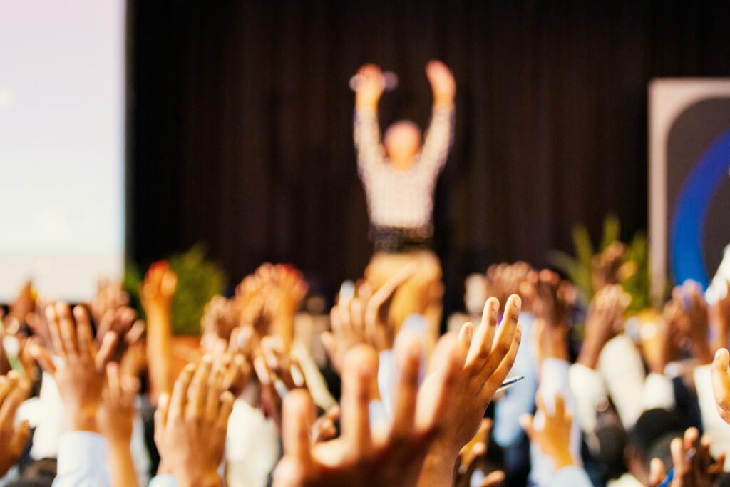 Publikum, welches die Hände in die Höhe hebt.